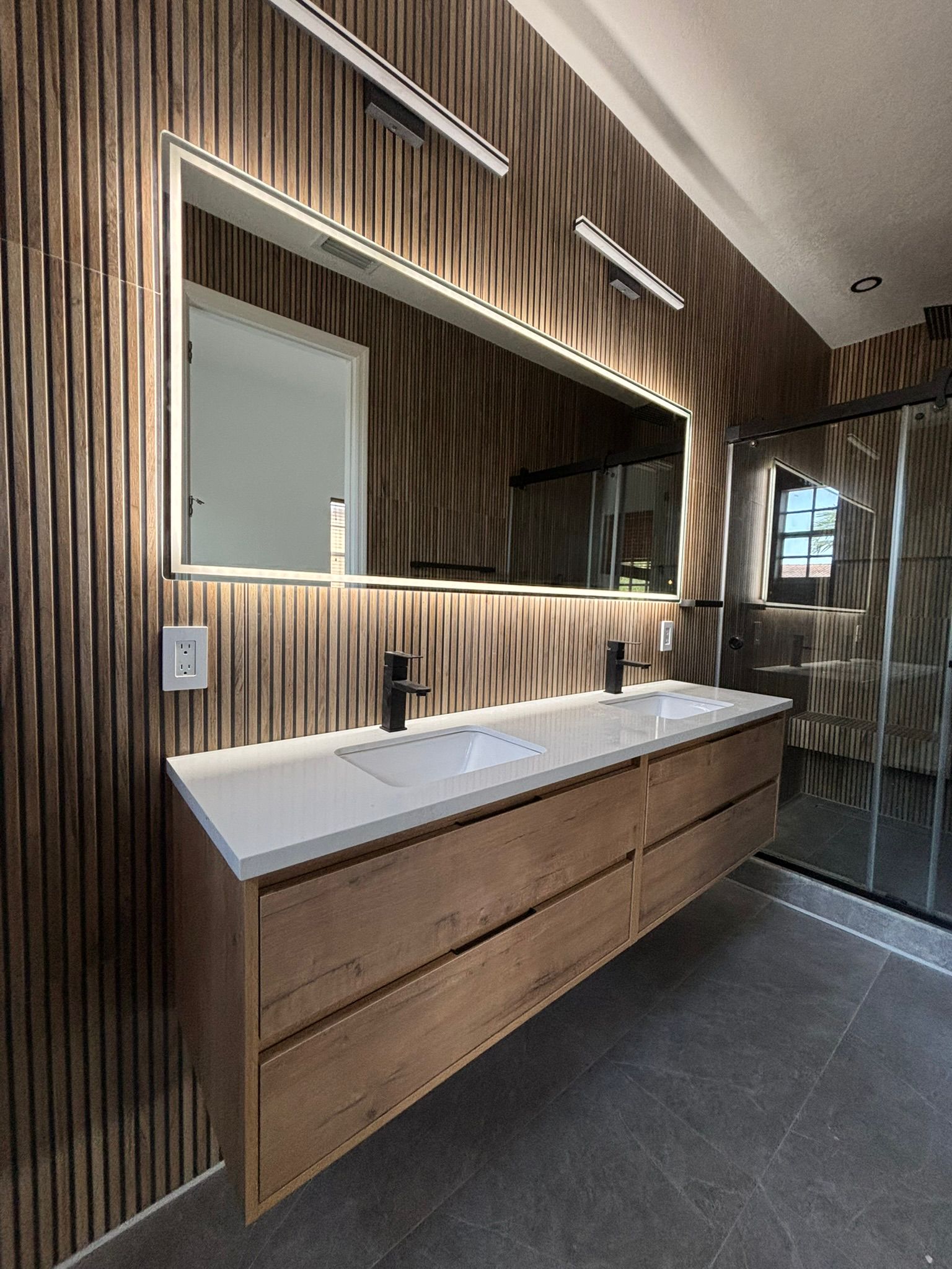 Modern bathroom with wooden vanity, double sink, and large mirror.